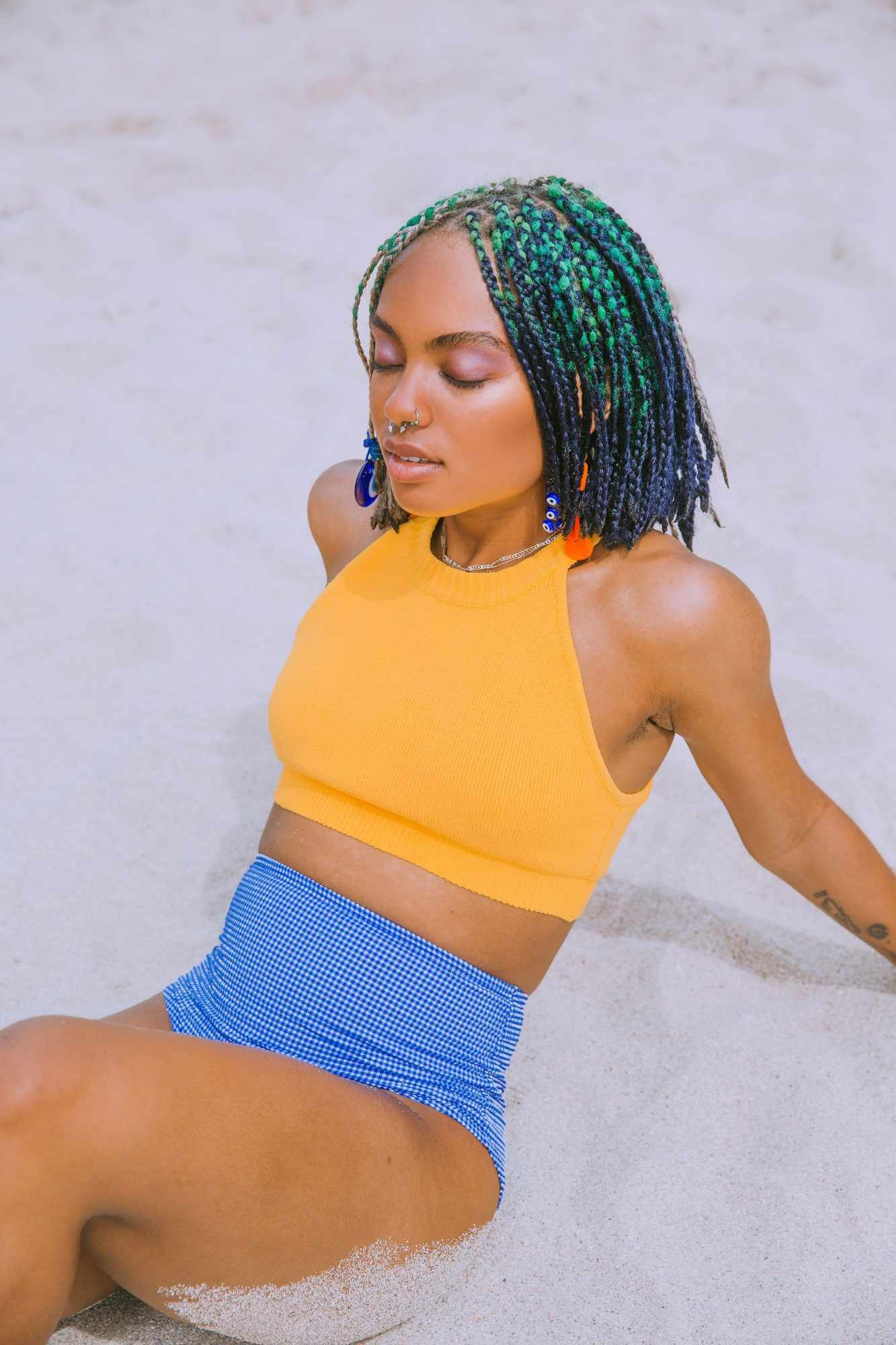 woman with protective hairdo sitting inch sand