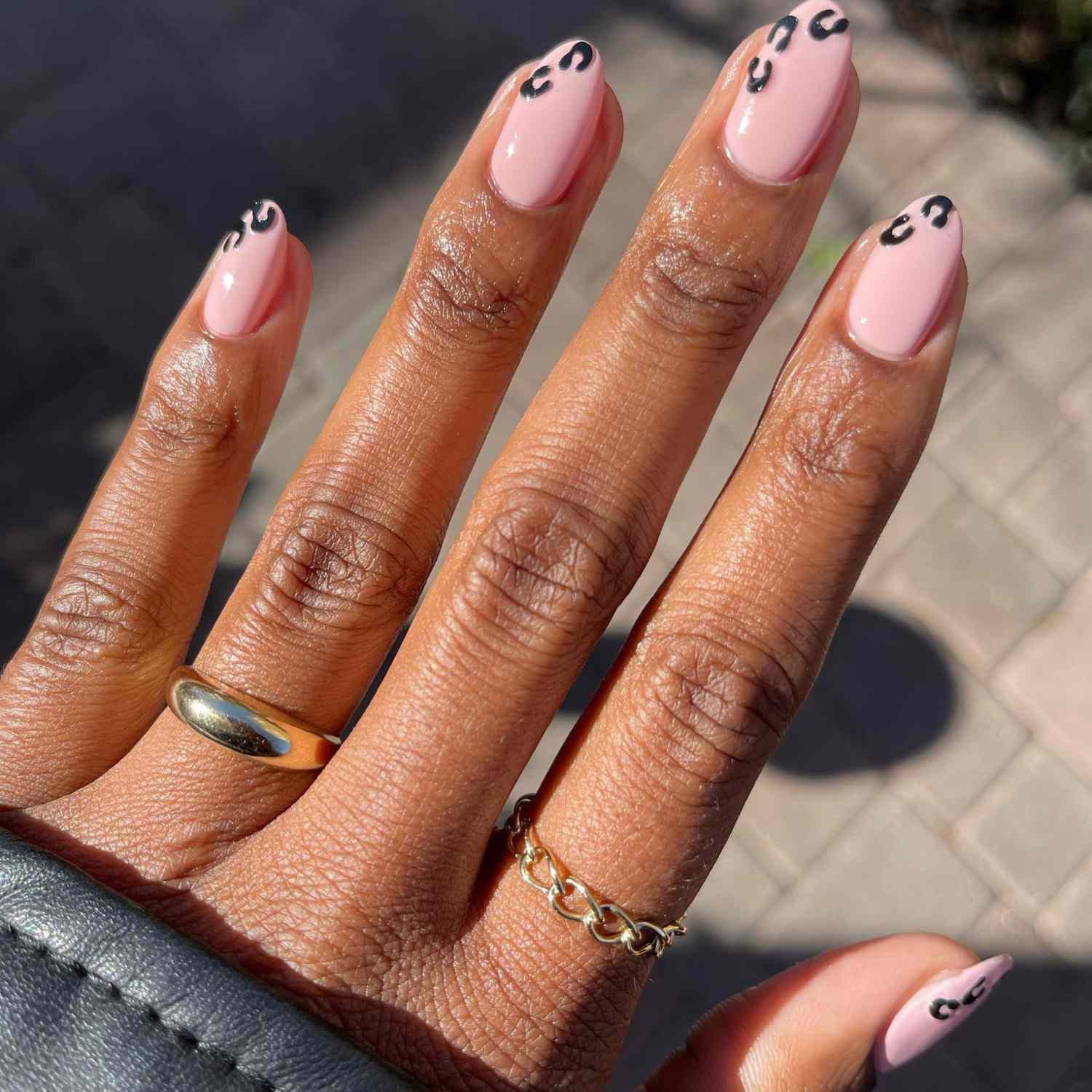 close up of nail with visible radiation pink manicure with black leopard print on tips