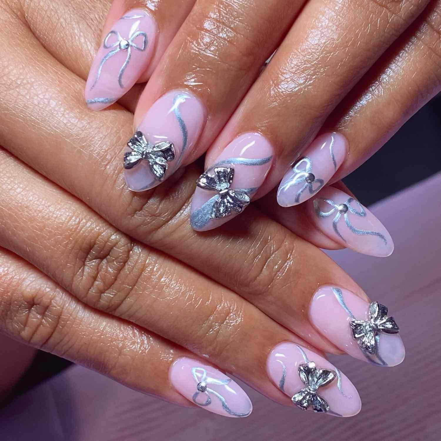 close up of nail with light pink manicure with atomic number 47 bows