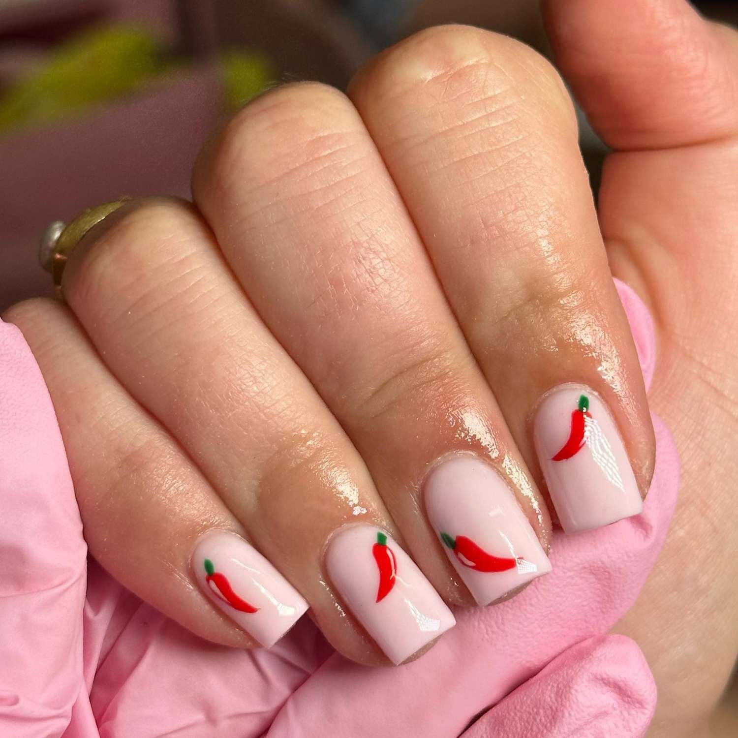 close up of nail with visible radiation pink manicure with chili pepper designing on each nail