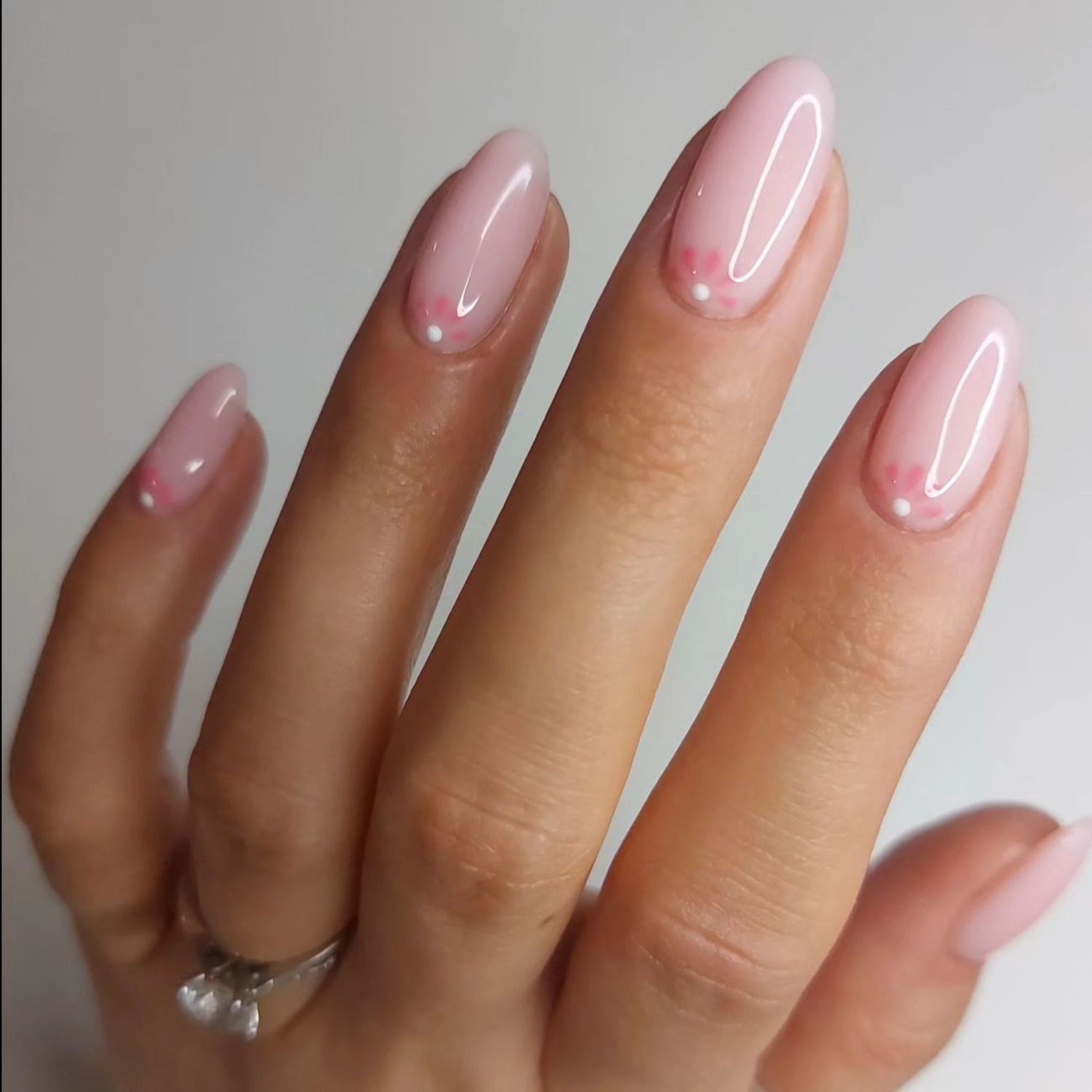 close up of nail with light pink manicure with flowered design finale to nail bed
