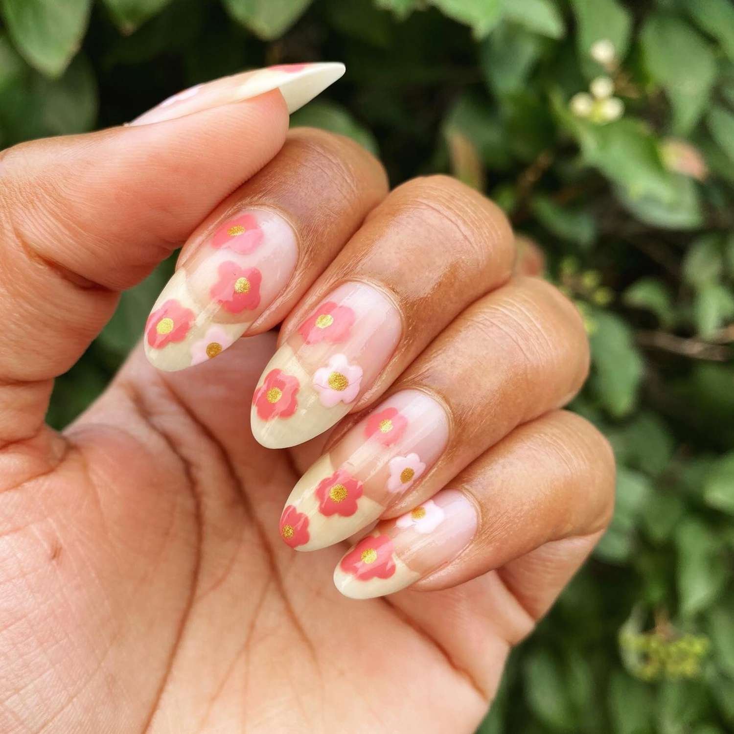 close up of nail with light pink manicure and yellow French tips with pink hand paint flowers