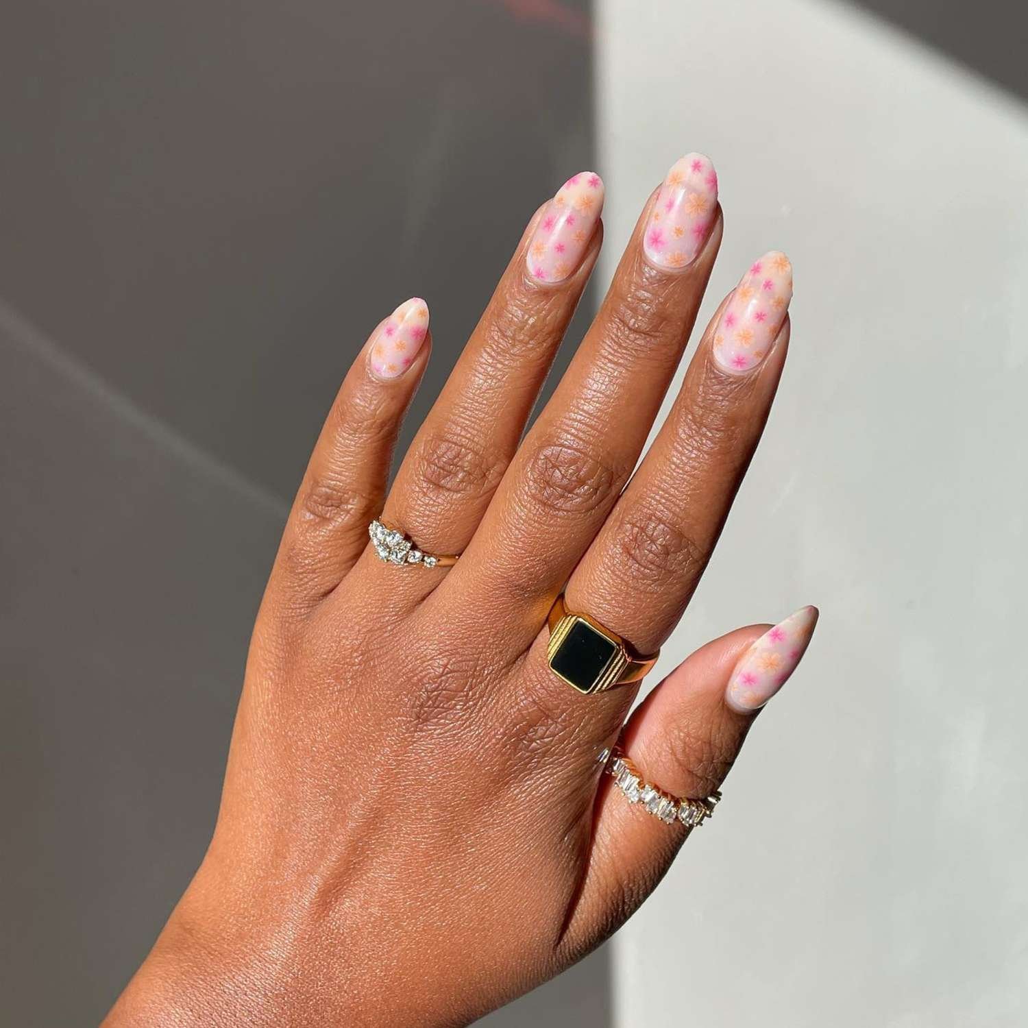 close up of nail with light pink manicure with pink and orange flowers
