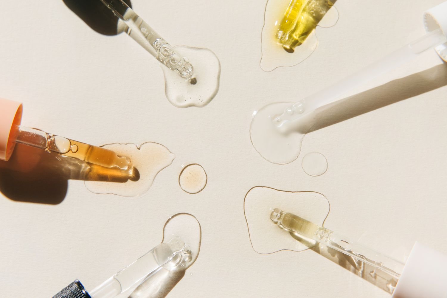 Pipettes with drops of cosmetic liquid on ecru background