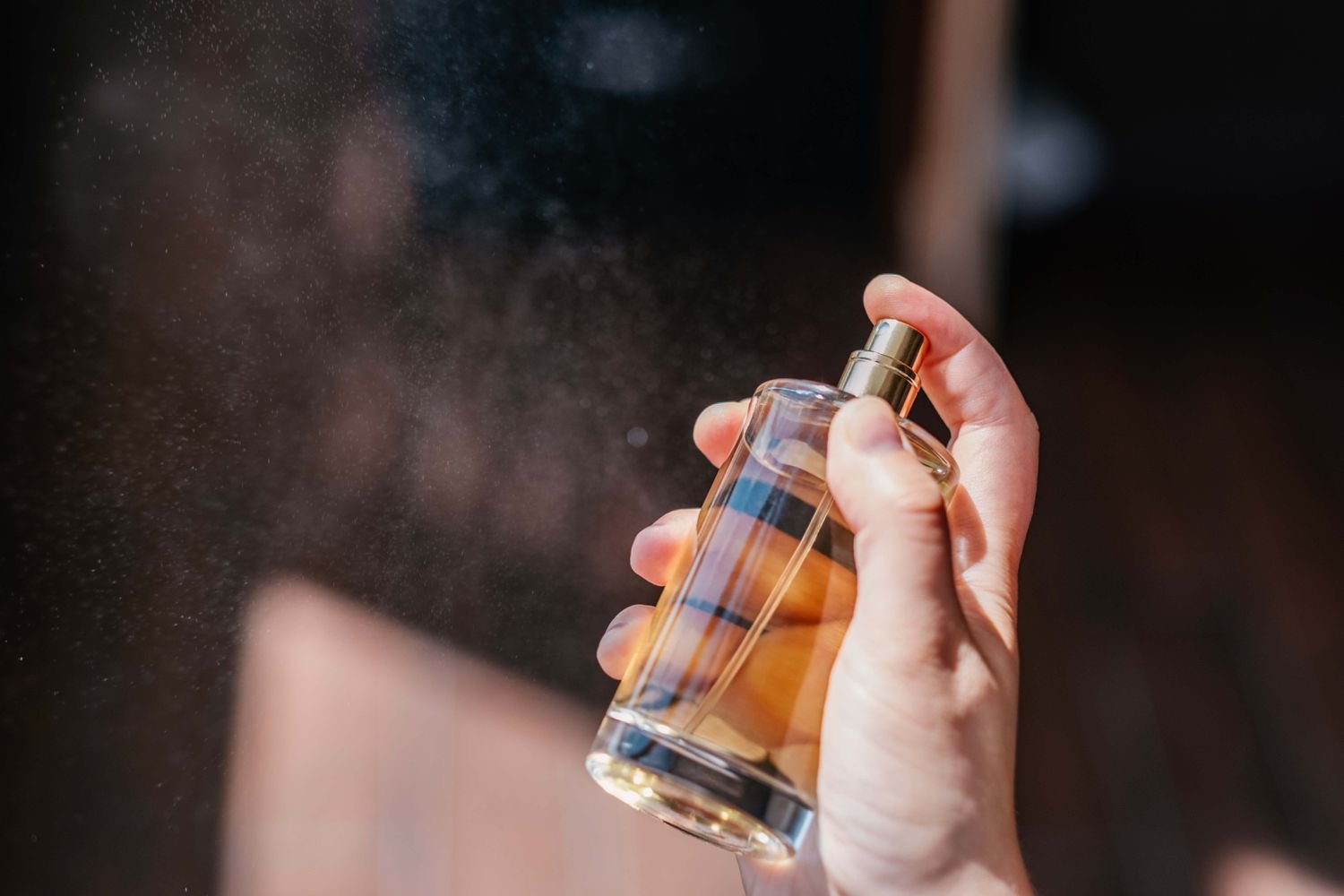 A adult female spritz perfume into the air.