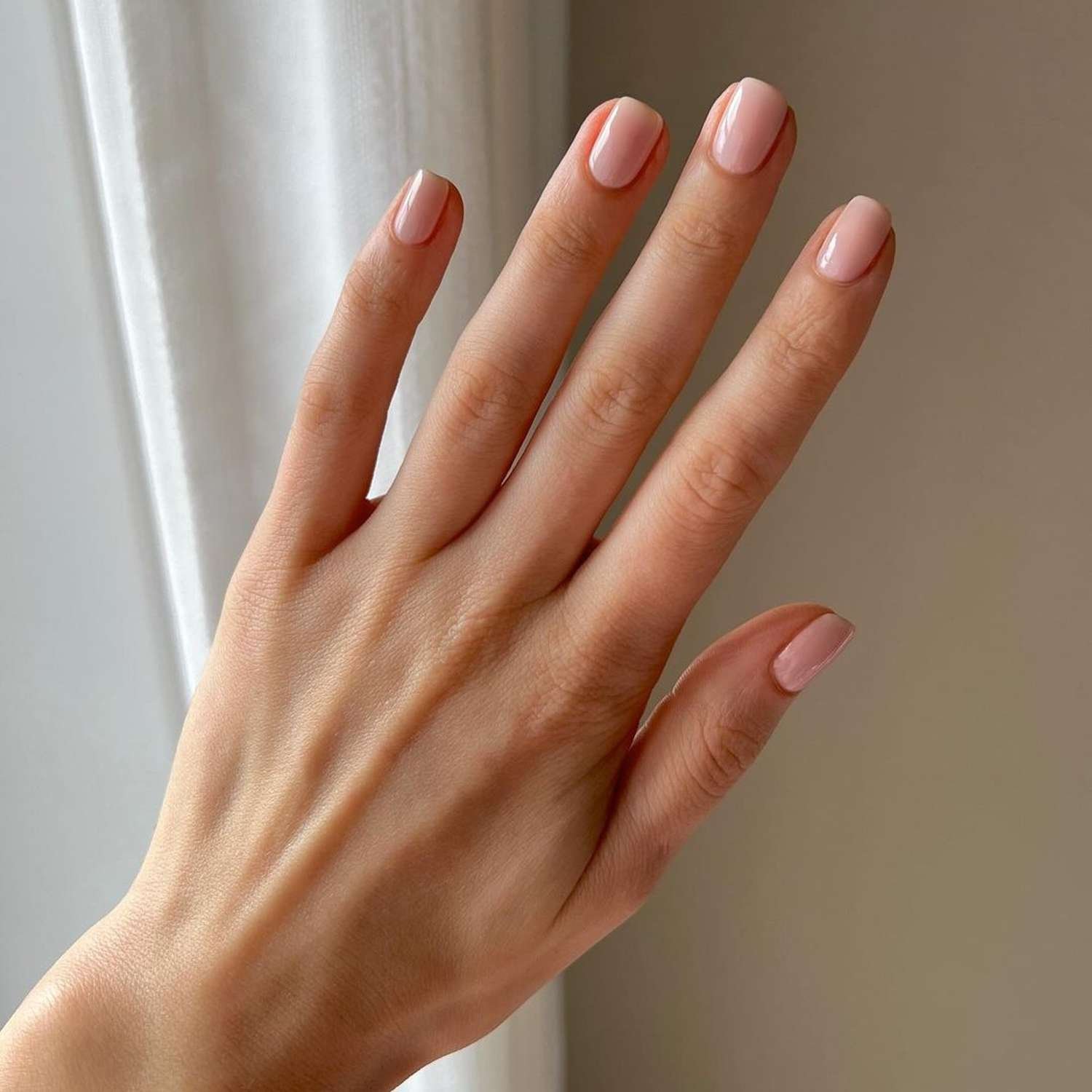 Hand showcasing a neutral blush jelly manicure