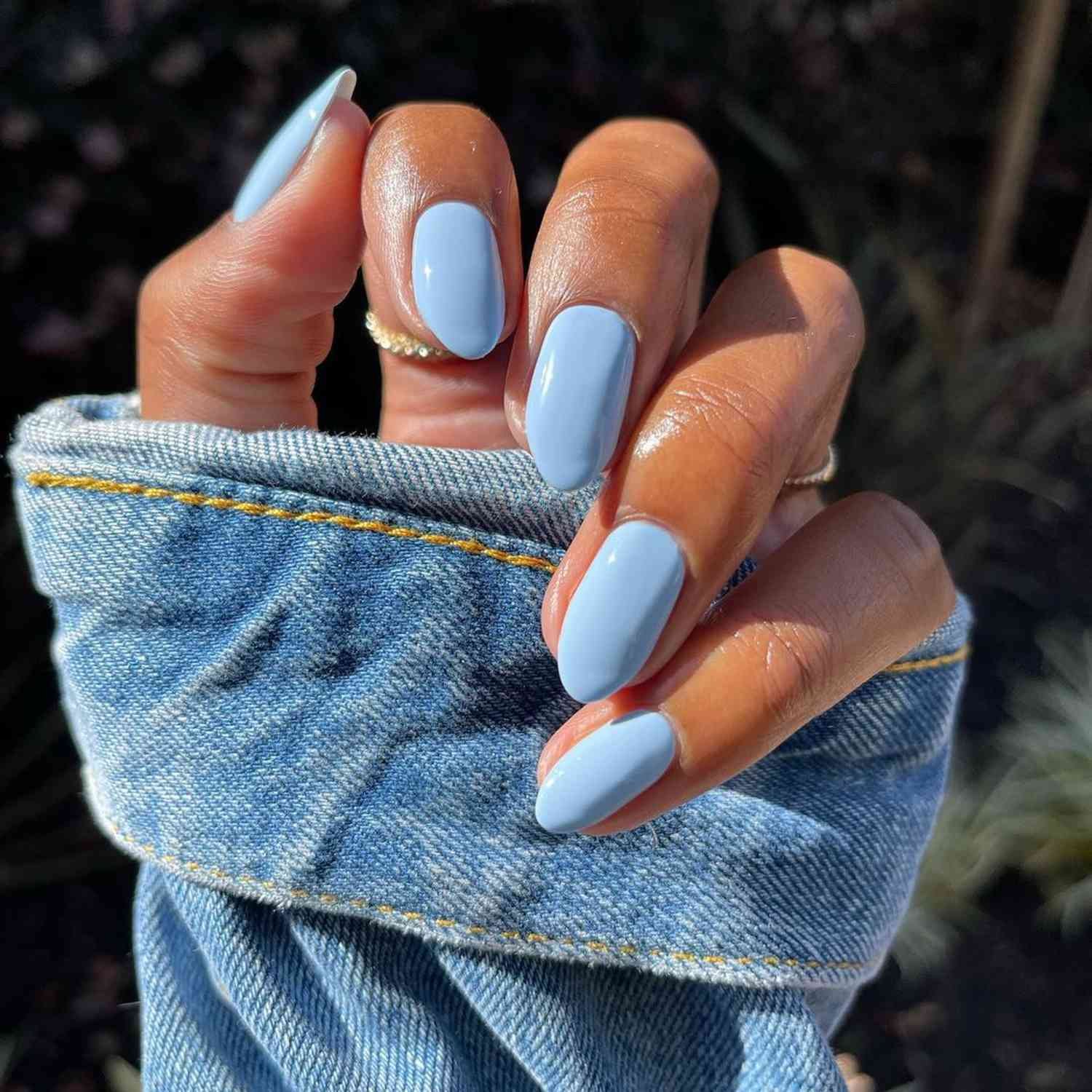 Periwinkle Nails inch a solid manicure against A denim jacket sleeve