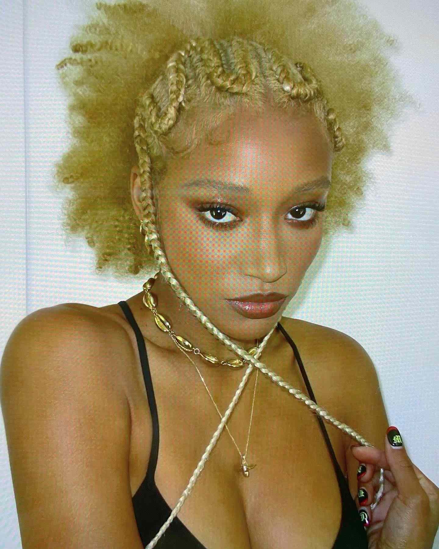 Amandla Stenberg with blond zig-zag braids and Associate in Nursing afro