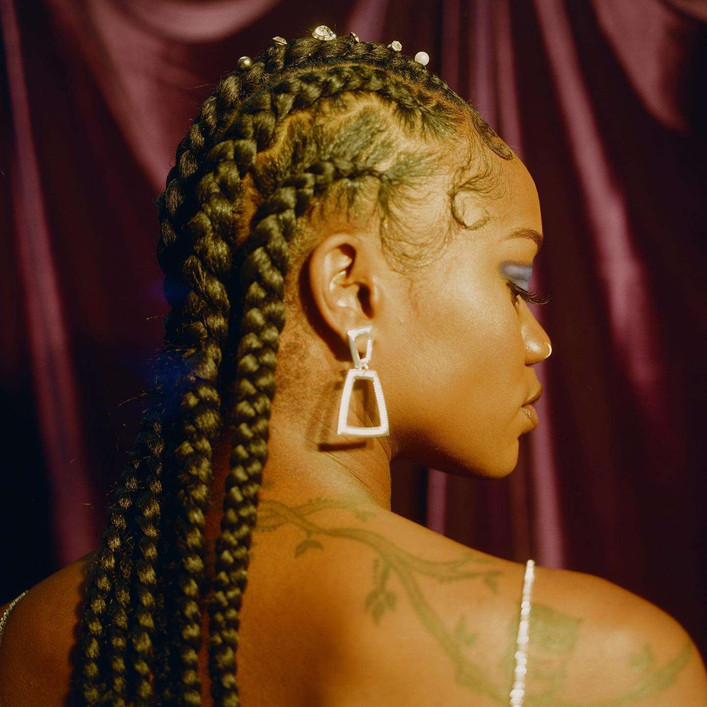 A somebody with chunky cornrows and rhinestone embellishments