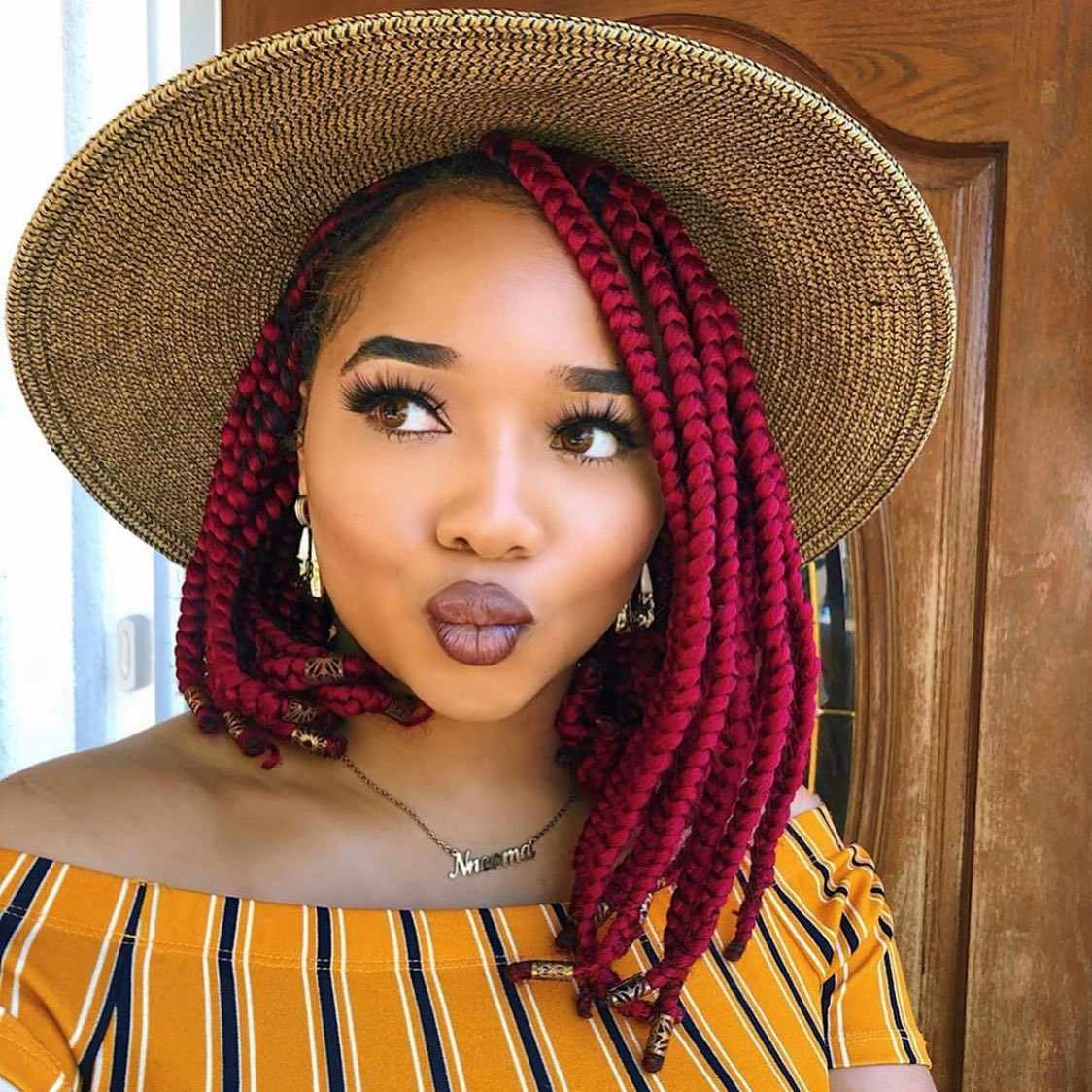 A person with angstrom vibrant red, short braided bob and gold embroidery at the ends