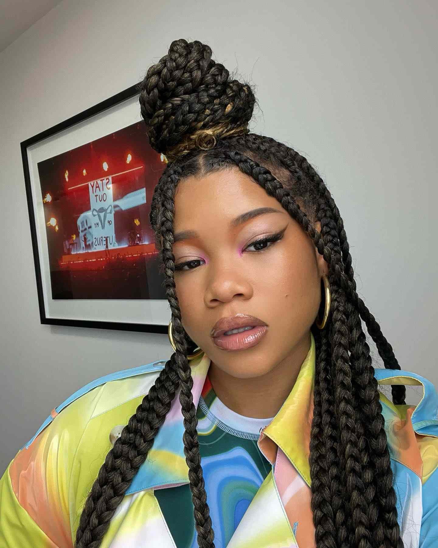 Storm Reid eroding long lumpy braids with A high half-up bun At the top